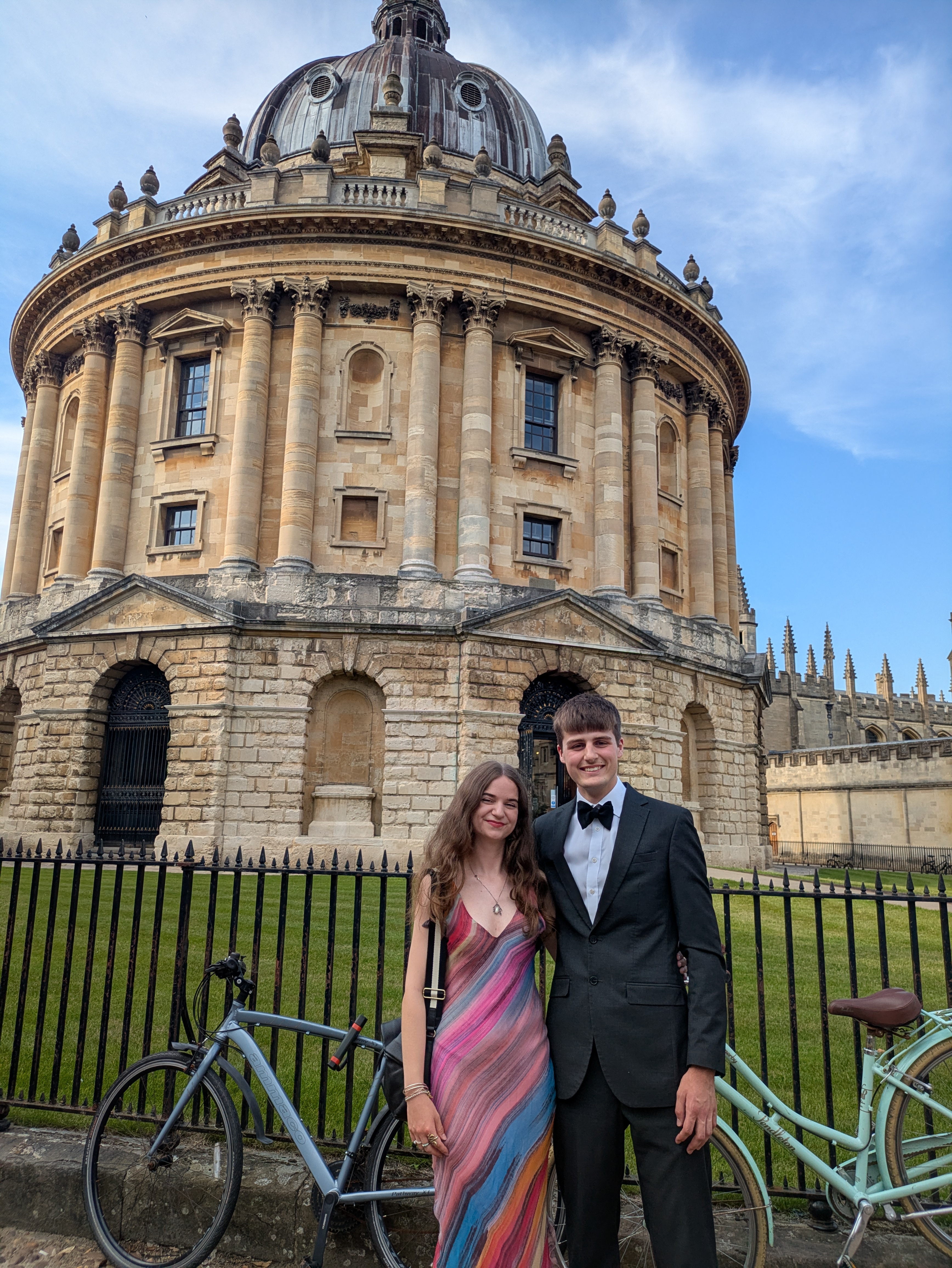 Grace and Leo in formal wear standing in front of the Radcliffe Camera, Oxford